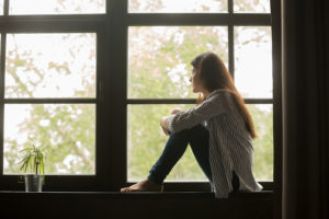 Woman staring out the window. Suffering from trauma symptoms? Learn to manage them with online trauma therapy in Winter Park, FL.