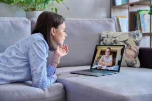 Image of a woman laying on her stomach speaking with an EMDR therapist virtually. With online therapy finding "EMDR near me" in Winter Park, FL is a lot easier. Whether in Orlando or across the state you can start EMDR therapy from home.